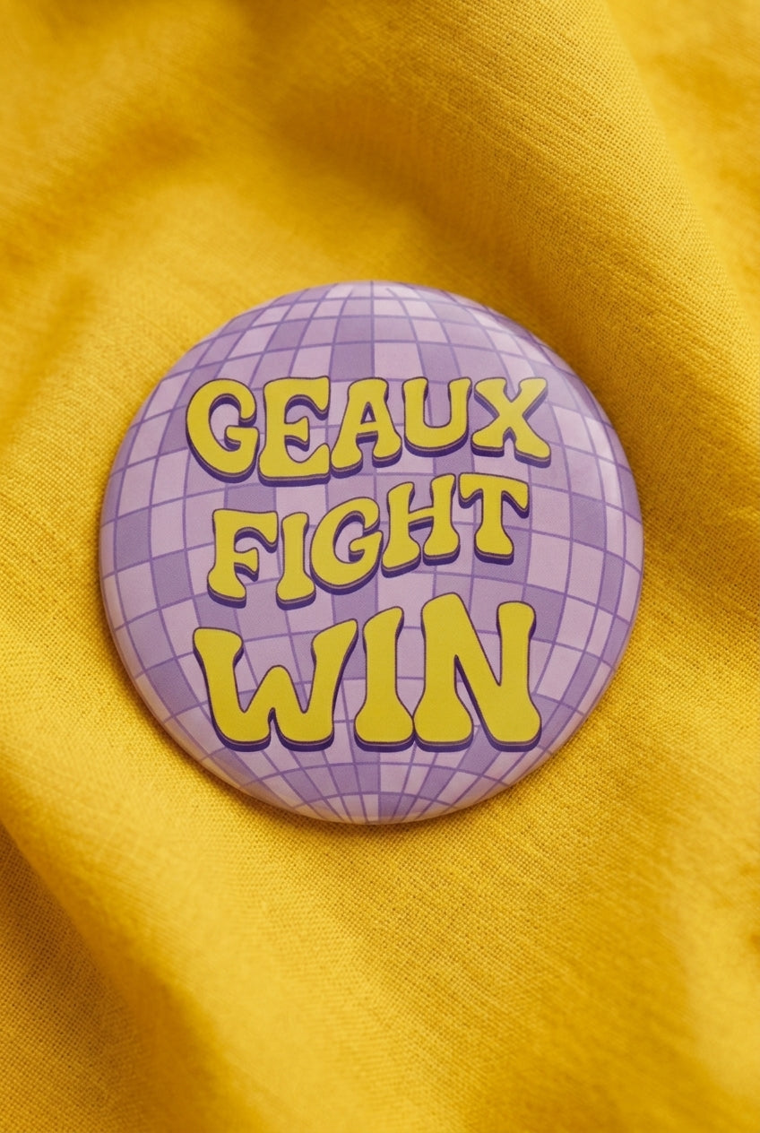 Geaux Fight Win Disco Button pinned on a yellow top