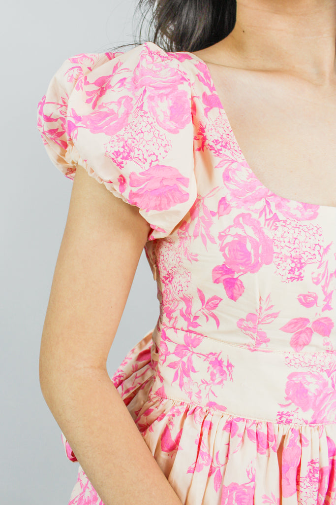 close up photo of tan puff sleeve dress with a pink floral pattern and a tiered ruffle skirt