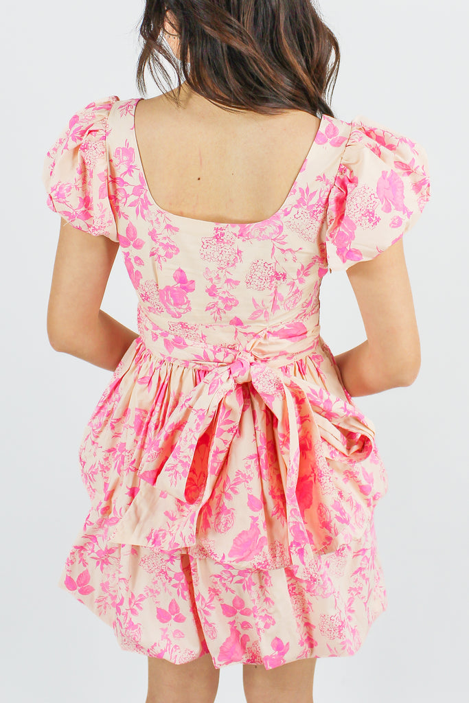 back photo of tan puff sleeve dress with a pink floral pattern and a tiered ruffle skirt