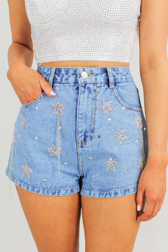 Front view of medium denim shorts with rhinestone and sequin star patches throughout.
