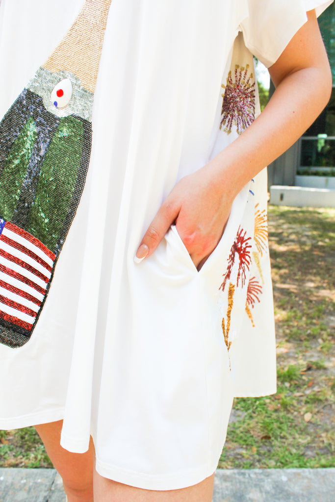 Side detail of Queen of Sparkles USA Champagne Ivory T-Shirt Swing Dress with sequin firework details on the back and oversized sequin american flag bottle on the front with photo showcasing the pocket detail