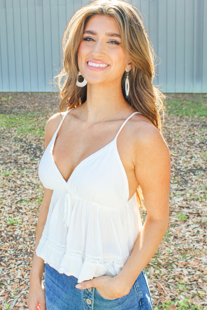 white flowy v-neck tank with a tie detail under the bust and crochet trim 