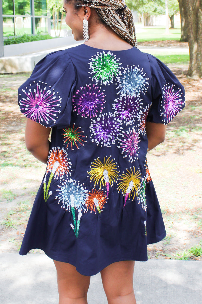 Queen of Sparkles navy blue dress with colorful sequin firework explosions on the back and subtle sequin pinstripes on the front. Has drop waist and puff sleeves. 