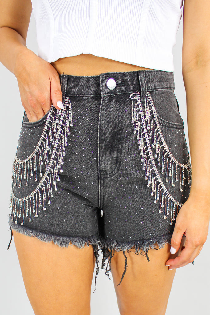 black denim shorts with rhinestone fringe detail along the front.