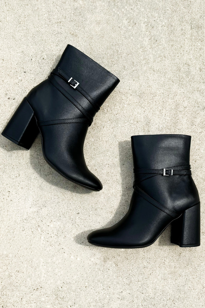 black pleather ankle boots with a strap wrapped around the ankle with a buckle