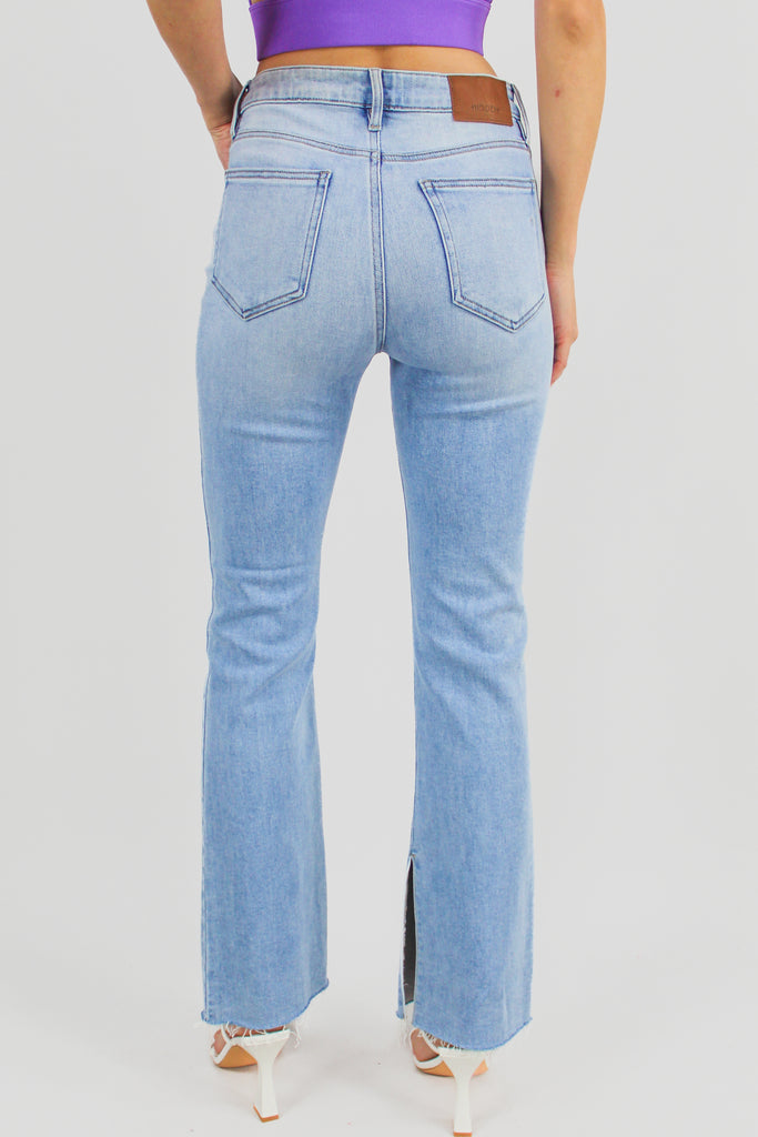 medium denim high rise jeans with a boot cut fit and side slit feature