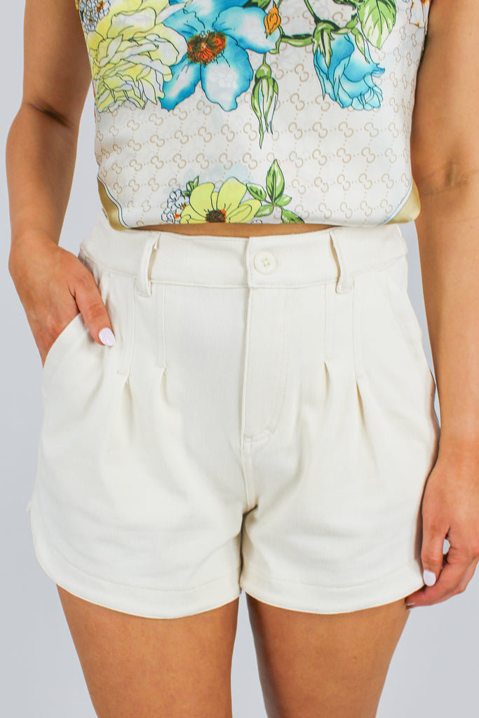 cream twill denim shorts with pleated detail in the front and a cinched waist in the back