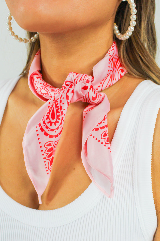 pink and red bandana silk scarf worn around neck, tied in the front