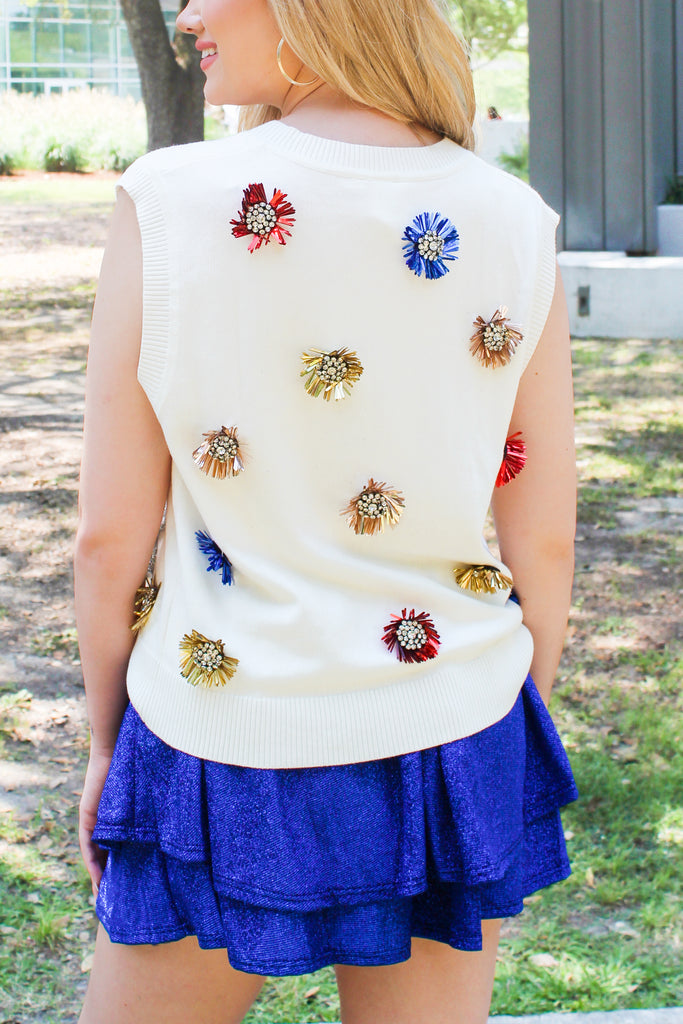 Back view of our Sparklers Sweater Vest by Queen of Sparkles comes in ivory with red, blue and silver sparkle tinsel trim creating cursive writing on the front under the vneck neck. this sleeveless sweater has red, blue and gold tinsel, embellished decals all over.