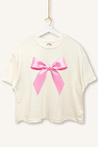 Charming Cues Ribbon Boxy Crop Tee in Cream with pink bow graphic on a white hanger