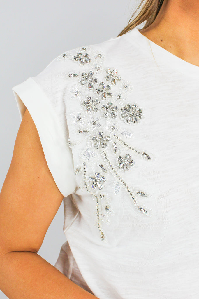 white cotton tank with cuffed sleeves and an embroidered and beaded detail on the shoulders