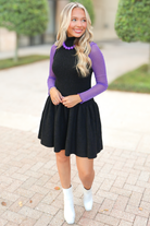 Sleeveless ribbed knit sweater dress layered over a purple shimmer mock neck mesh top