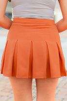 Burnt orange pleated high waisted mini skirt, back view